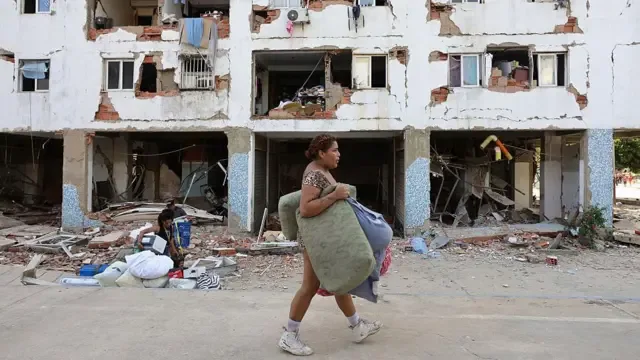 Una mujer pasa por delante de un edificio que sufrió extensos daños.