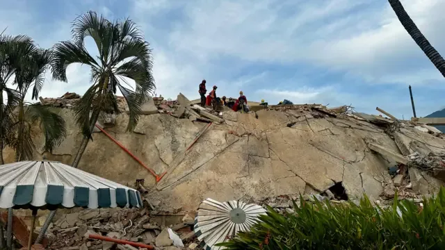 Escombros sobre el conjunto residencial Caribe, en la parroquia Caraballeda, estado La Guaira. En la cima de la pila de escombros se ve un pequeño grupo de rescatistas.