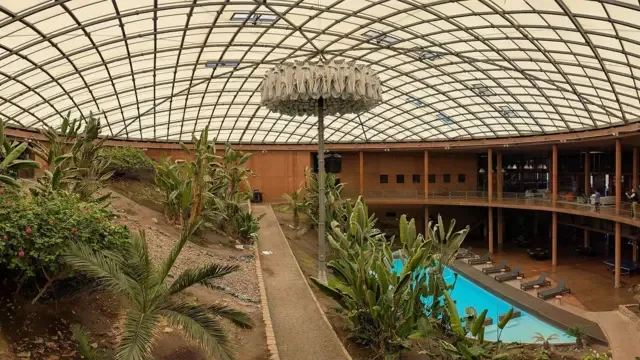 Plantas junto a lo que parece ser una piscina, bajo una cúpula translúcida.