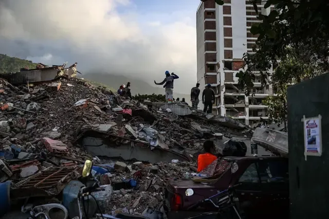 Un grupo de personas paradas sobre escombros acumulados.